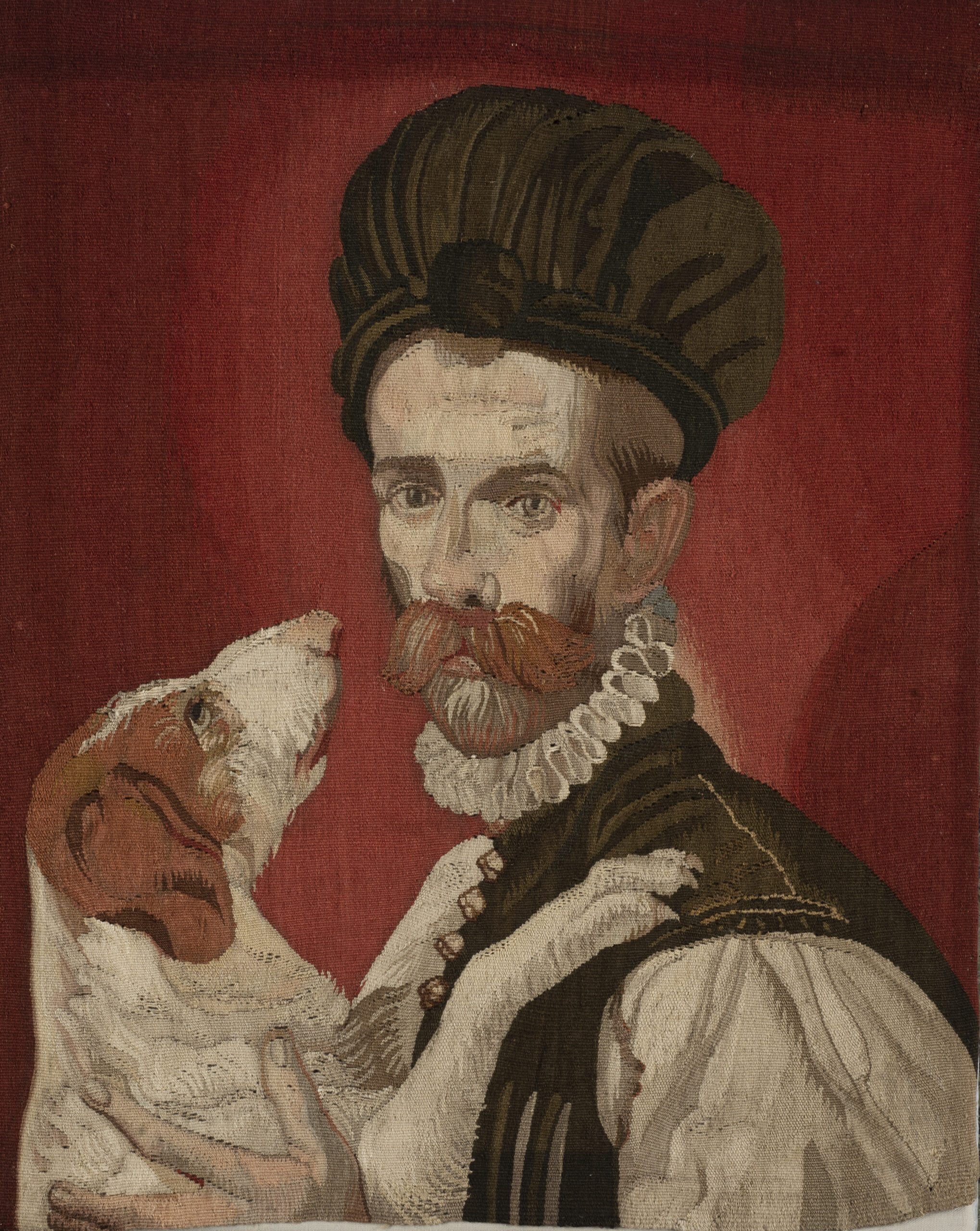 Maestro arazziere attivo tra XVIII e XIX secolo      
Ritratto d’uomo con cane
Copia dal Ritratto d’uomo con cane di Bartolomeo Passarotti ai Musei Capitolini
Filato in lana e seta 
cm 65X42



Fiore all’occhiello dell’Ospizio Apostolico del San Michele furono le officine di arazzeria a Porta Portese che nel XVIII secolo fecero concorrenza alle grandi manifatture francesi nella fornitura dei pregiati arredi per palazzi nobiliari e pubblici.
Oltre ai grandi arazzi da sala le officine si specializzarono anche in formati più piccoli che riproducevano nelle esatte dimensioni dell’originale dipinti su tavola e tela, come in questo caso: il soggetto è la copia di un dipinto di Bartolomeo Passarotti raffigurante un gentiluomo con un cane e datato alla fine del Cinquecento, oggi conservato ai Musei Capitolini.