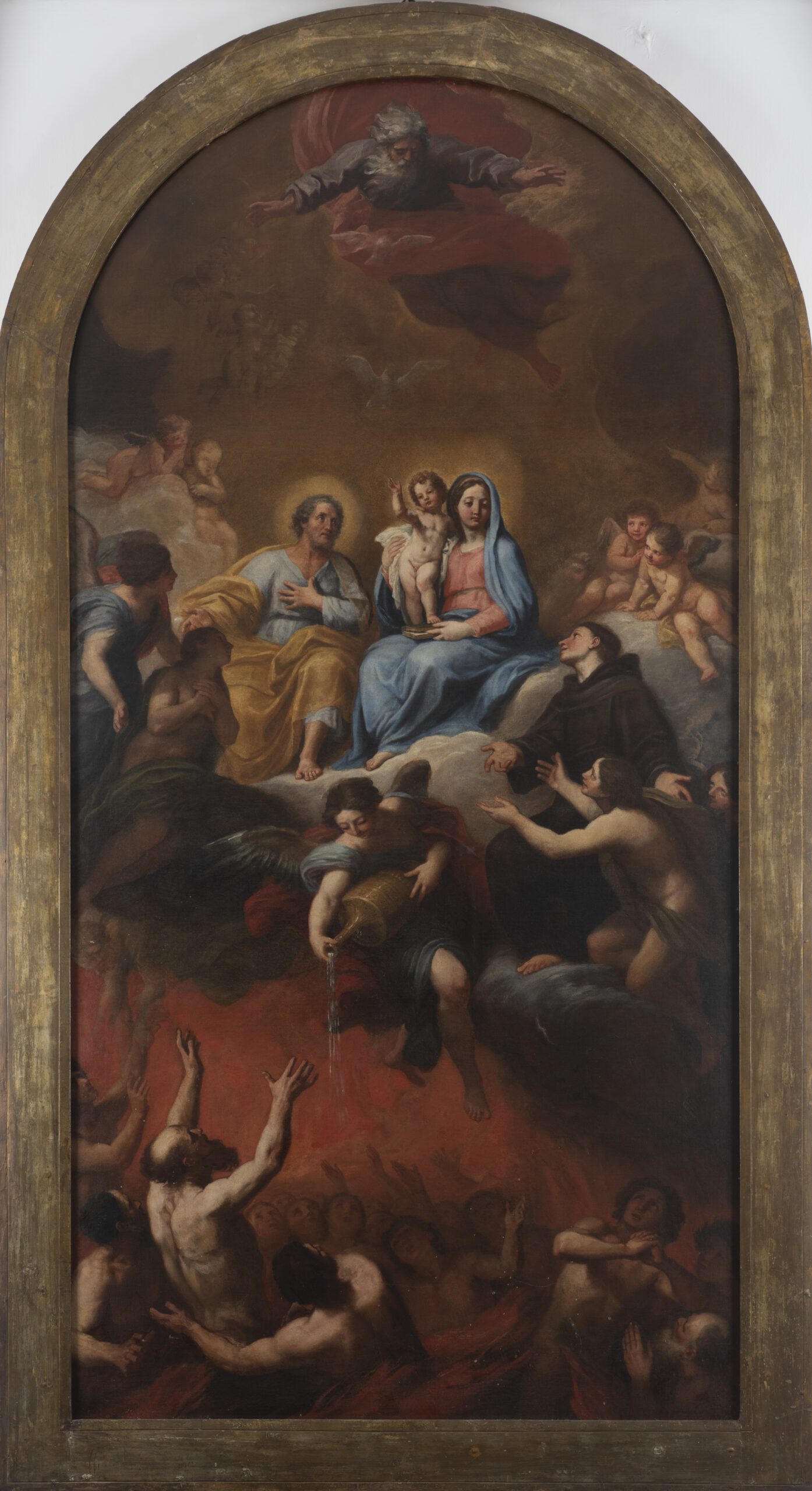 Cerchia di Gaetano Lapis La SS. Trinità, Sacra Famiglia, S. Antonio, putti e angeli porgono acqua alle anime del Purgatorio Olio su tela cm. 248 x 127 Metà del XVIII secolo La grande tela, che conserva ancora la cornice dorata originale, è da considerare una pala d’altare, ovvero un dipinto di grandi dimensioni che, collocato su un altare laterale di una chiesa antica, dava risalto ad un soggetto di devozione popolare accompagnando i fedeli verso l’altare maggiore. Il soggetto non deve trarre in inganno: le Sacre Persone nella parte alta del quadro intercedono per le anime nella parte sottostante; esse sono avvolte dalle fiamme, le quali però non vanno intese come quelle punitive dell’Inferno ma come una forza purificatrice che porterà di nuovo alla vicinanza con Dio. In tal senso gli angeli alleviano con l’acqua un dolore momentaneo che troverà fine nell’ingresso al Paradiso. Lo stile raffaellesco delle figure e le tonalità pastello, assieme a una grande padronanza nella gestione dello spazio, testimoniano un maestro centro italiano vicino ai modi di Gaetano Lapis, detto anche il Carraccetto, figura chiave nell’evoluzione del linguaggio barocco nelle Marche.